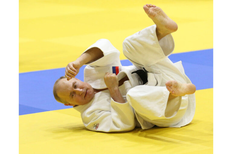 Kriegsverbrecher Putin auf einem Tatami bei ukrainischer Flagge. Foto Getty Images.