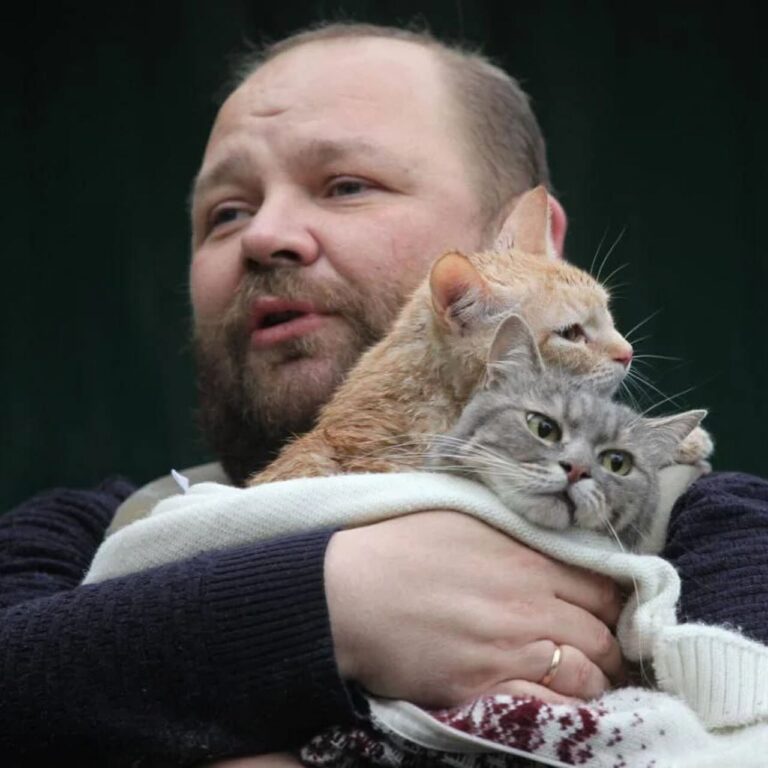 Чоловік виносить двох котів з будівлі, яку обстріляли окупанти. Фото: Mykola Synelnykov для Reuters
