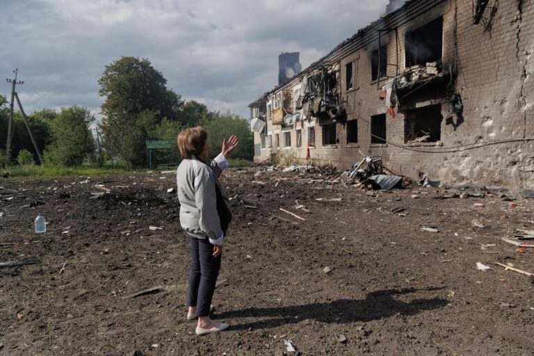 Жінка показує на обстріляний силами РФ житловий будинок. Фото: Yakiv Liashenko