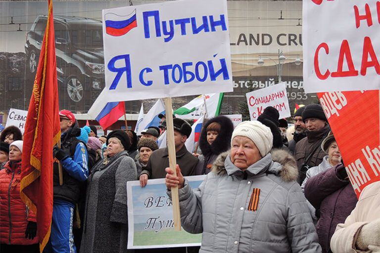 Uma mulher russa segura um cartaz com as palavras "Putin, estou contigo"