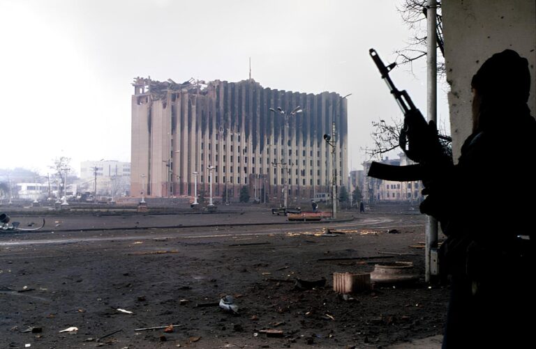 1. A Chechen fighter stands near the government palace building during a short lull in fighting in Grozny, Photo_ Mikhail Evstafiev