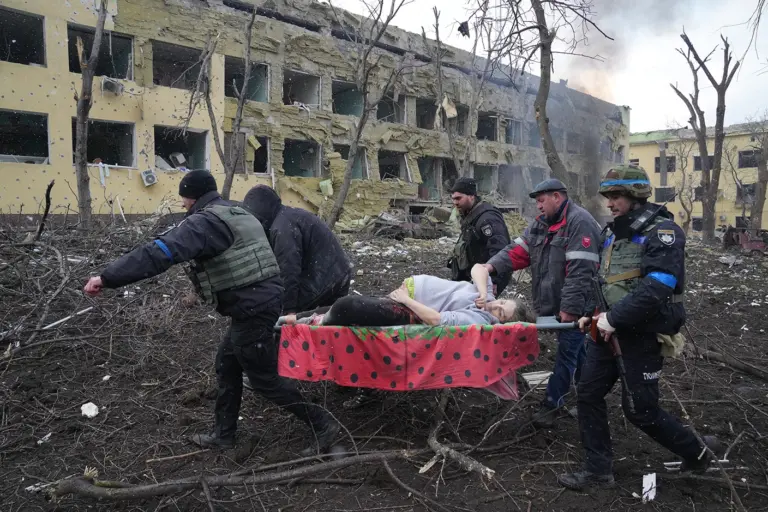 Поранену Ірину Калініну виносять на ношах із пологового будинку в Маріуполі після російського авіаудару. Фото: Євген Малолєтка.