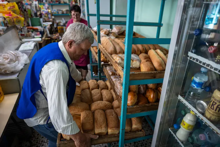 Працівник пекарні агрофірми викладає хліб на стелаж. Фото: Максим Кішка.