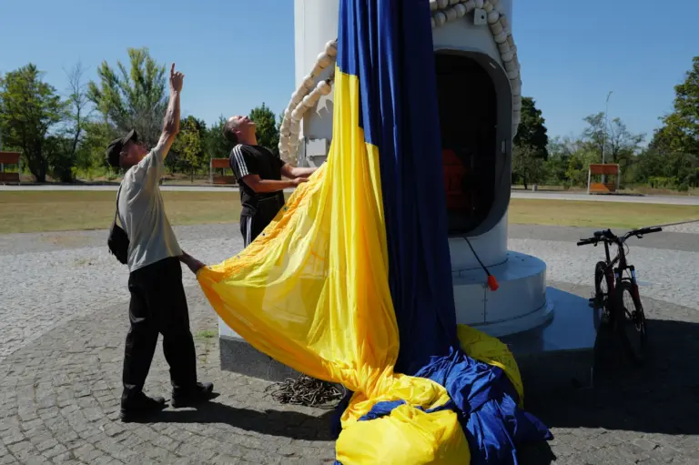 Ранок 23 серпня, День прапора. Біля флагштока комунальники чіпляють до троса величезне жовто-блакитне полотно. Фото: В'ячеслав Ратинський.