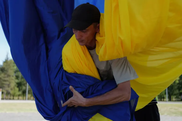 Ранок 23 серпня, День прапора. Біля флагштока комунальники чіпляють до троса величезне жовто-блакитне полотно. Фото: В'ячеслав Ратинський.